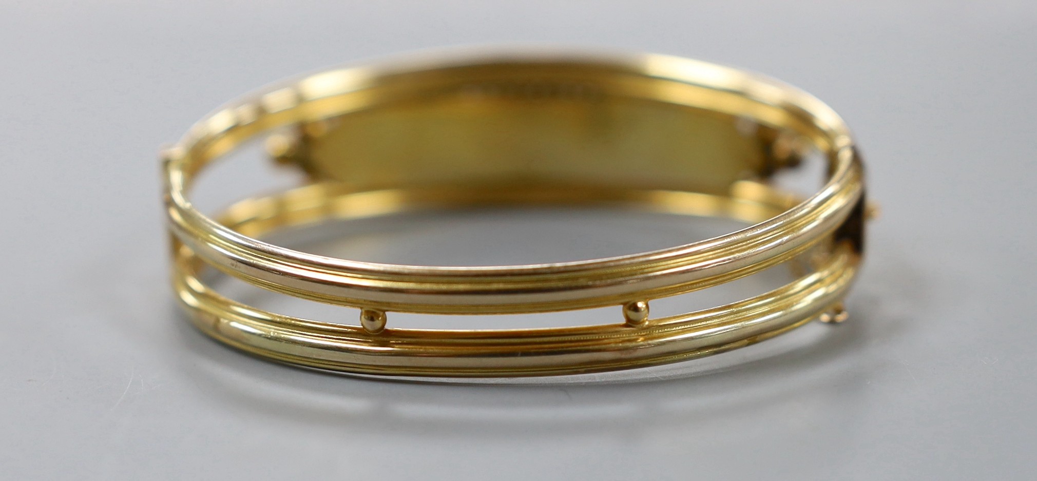 An Edwardian 9ct gold and three stone garnet and two stone diamond chip set hinged bangle, gross weight 12.5 grams.